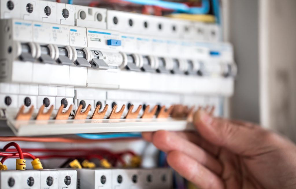 electrical technician working switchboard with fuses installation connection